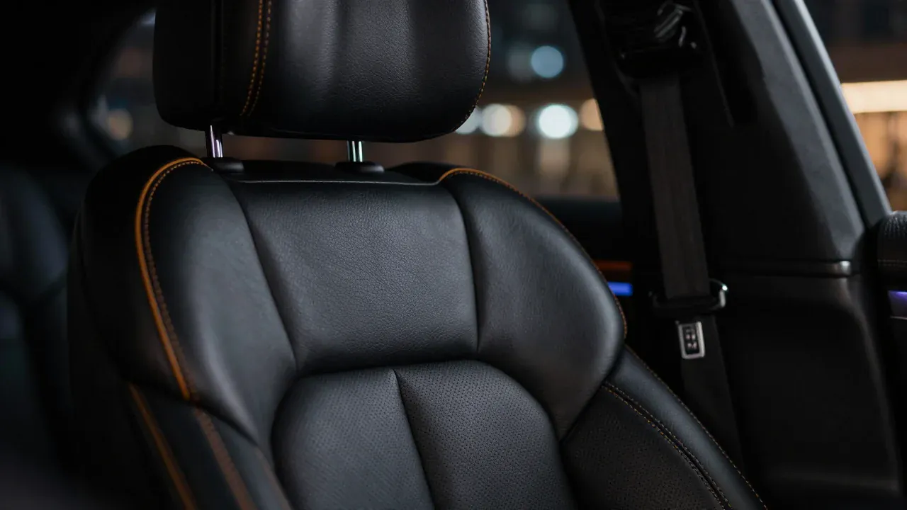 Close-up of a dark leather car interior with amber stitching